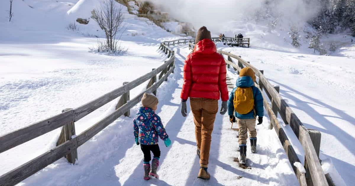 Woman walks on a snow-covered boardwalk in Yellowstone with two kids. (Representative Cover Image Source: Getty Images | Jordan Siemens)