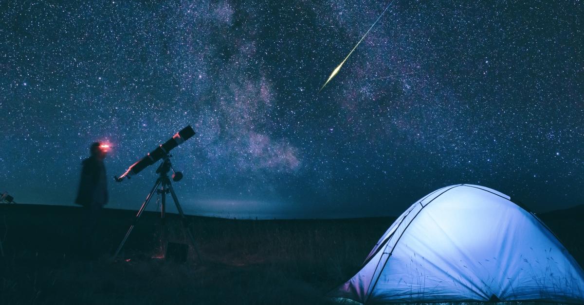 People with telescope camping and watching meteor shower.