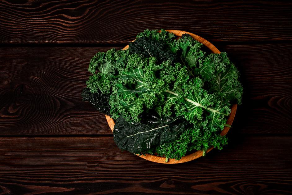 Kale leaves in a bowl on a wooden table. 