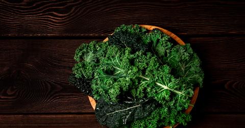 Kale leaves in a bowl on a wooden table.