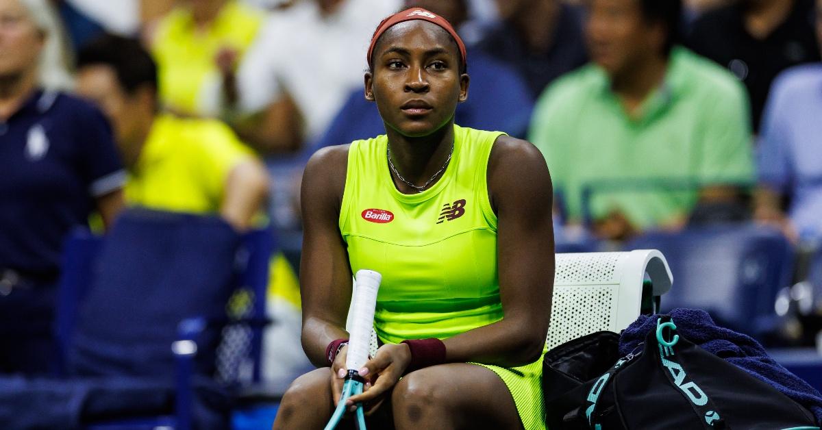 Tennis player Coco Gauff sits while her match is delayed by climate activists.