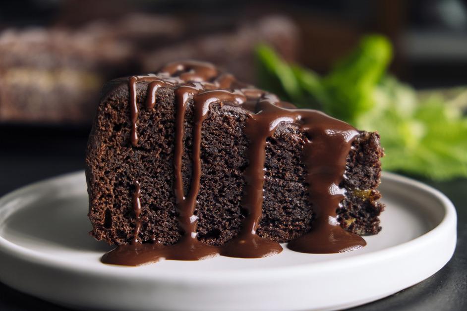 A slice of chocolate cake with chocolate fudge dripping down the side. 