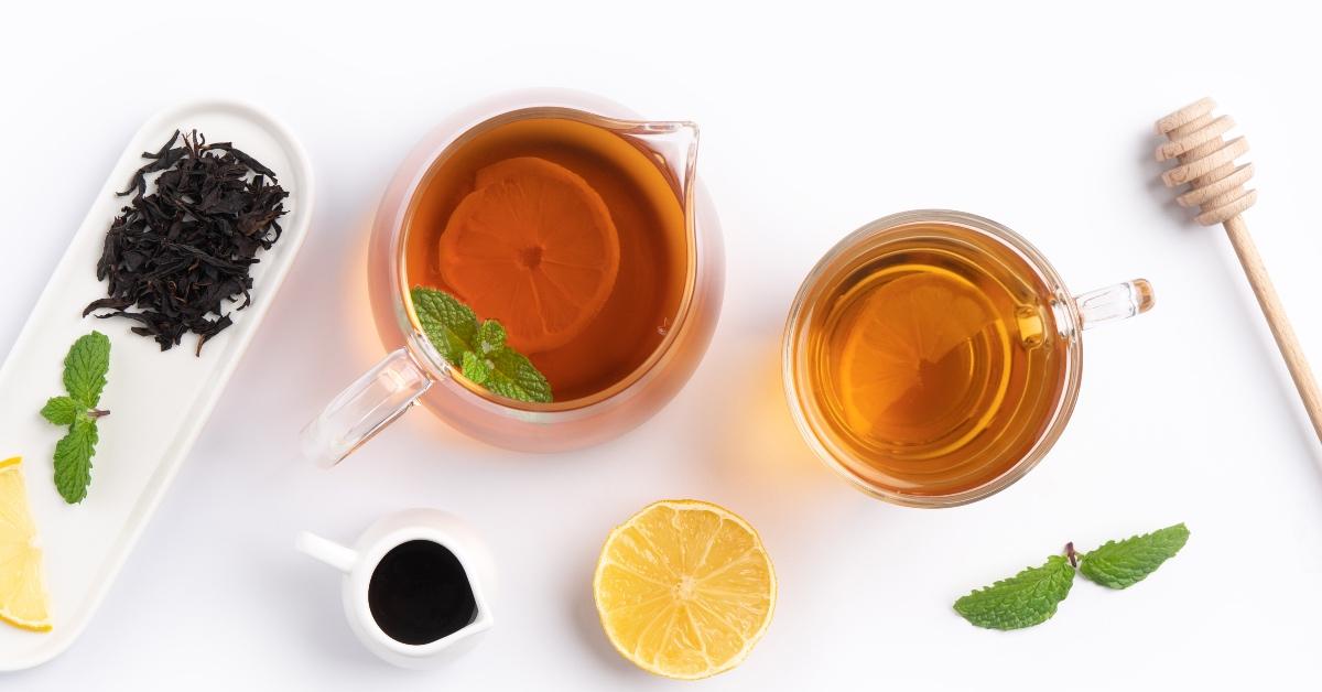 Photograph of black tea being brewed with lemon, honey and mint.