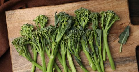 Uncooked broccoletti spread out on a wood cutting board.
