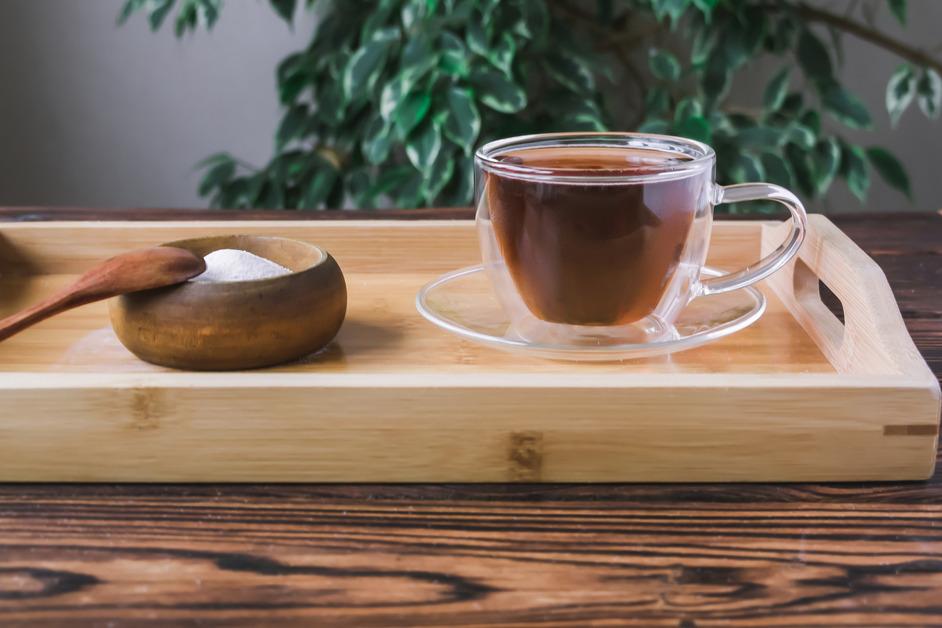 Stevia powder next to a cup of tea. 