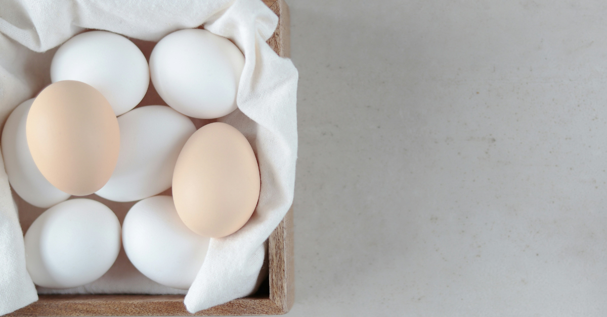 A closeup of a collection of white and brown chicken eggs sitting in a box