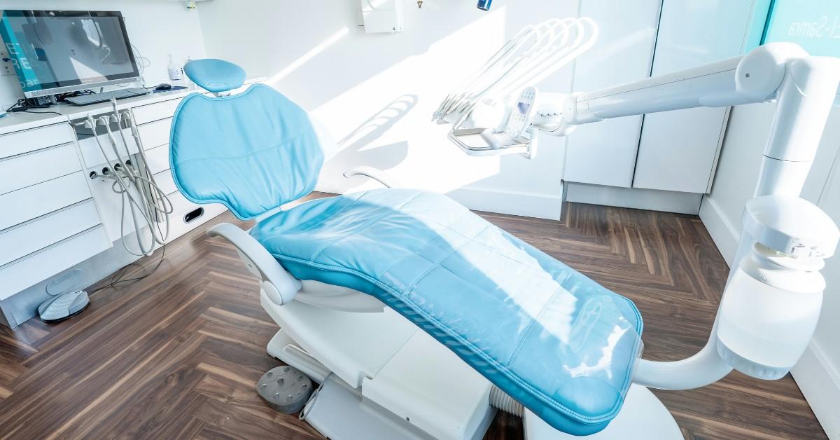 An exam chair sits in the middle of a stark dental office