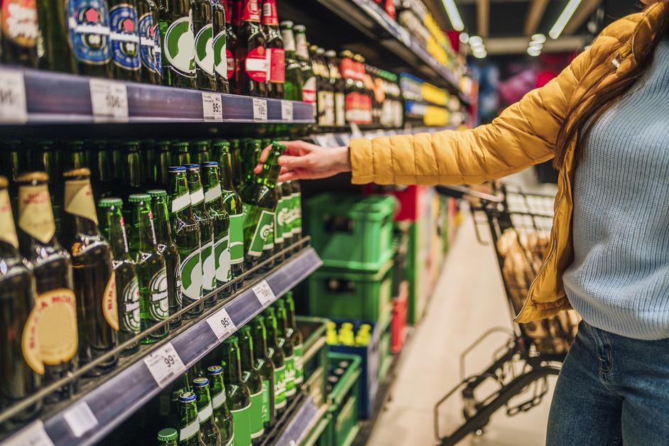 A woman at the store pinks out a single beer from the aisle of alcohol 