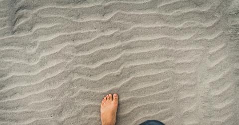 man stepping barefoot in sand