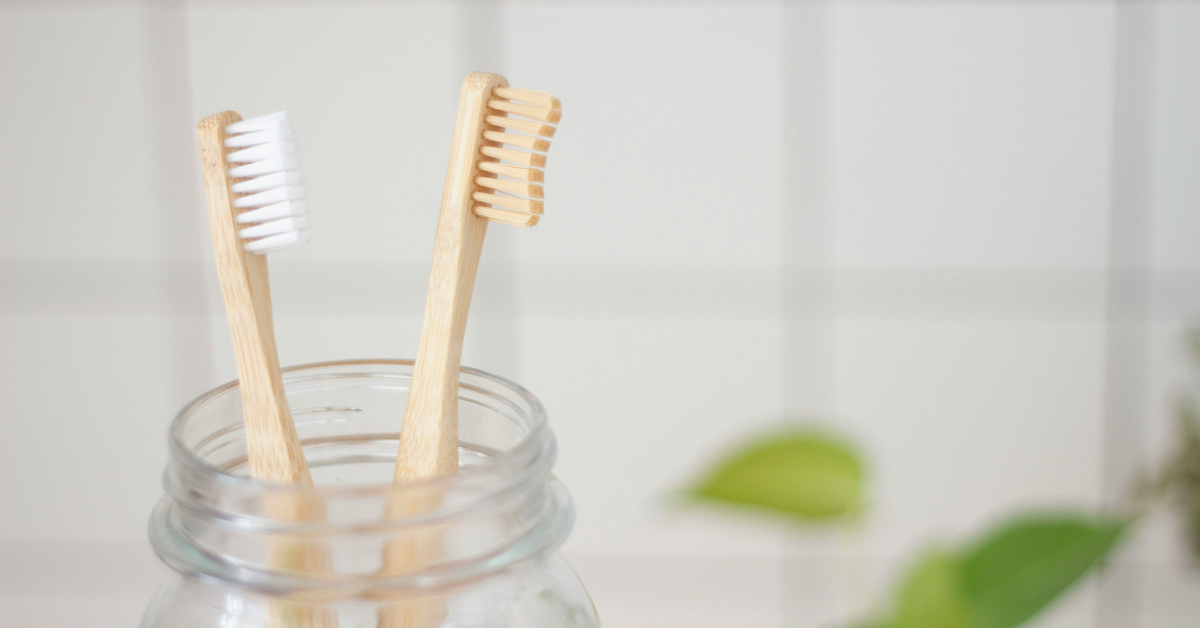 A closeup of a pair of toothbrushes being stored in a glass jar
