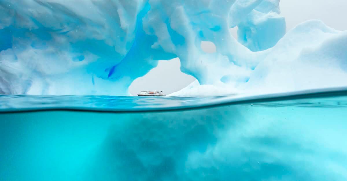 Vast image showing a massive iceberg above and below the surface of the water