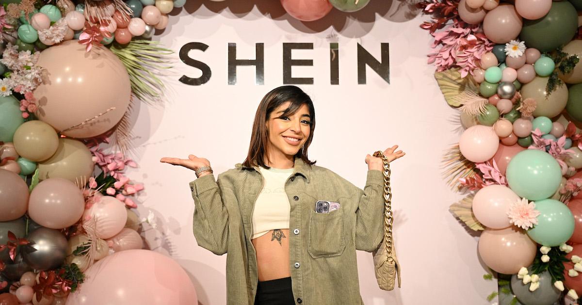 Manrika Khaira smiles in front of a pink backdrop that says Shein