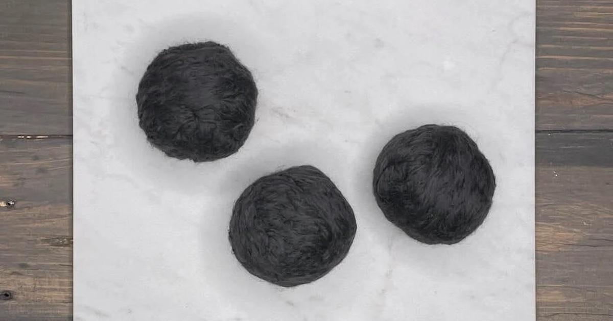 Three gray dryer balls on a counter