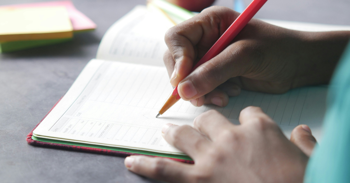 A child fills out a journal with a pen