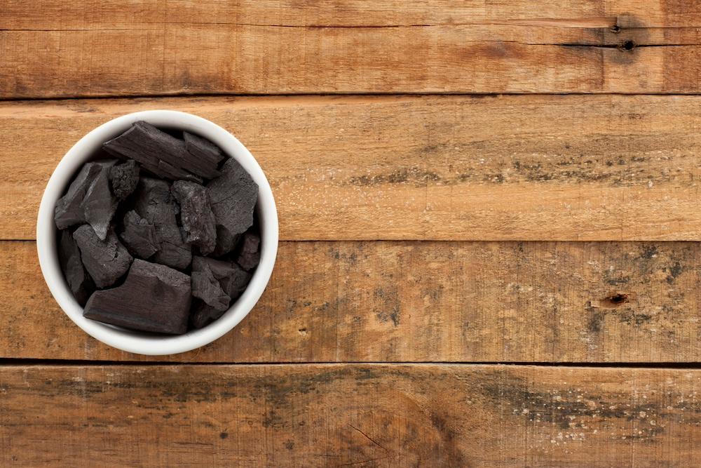 A bowl of charcoal on a wooden surface.