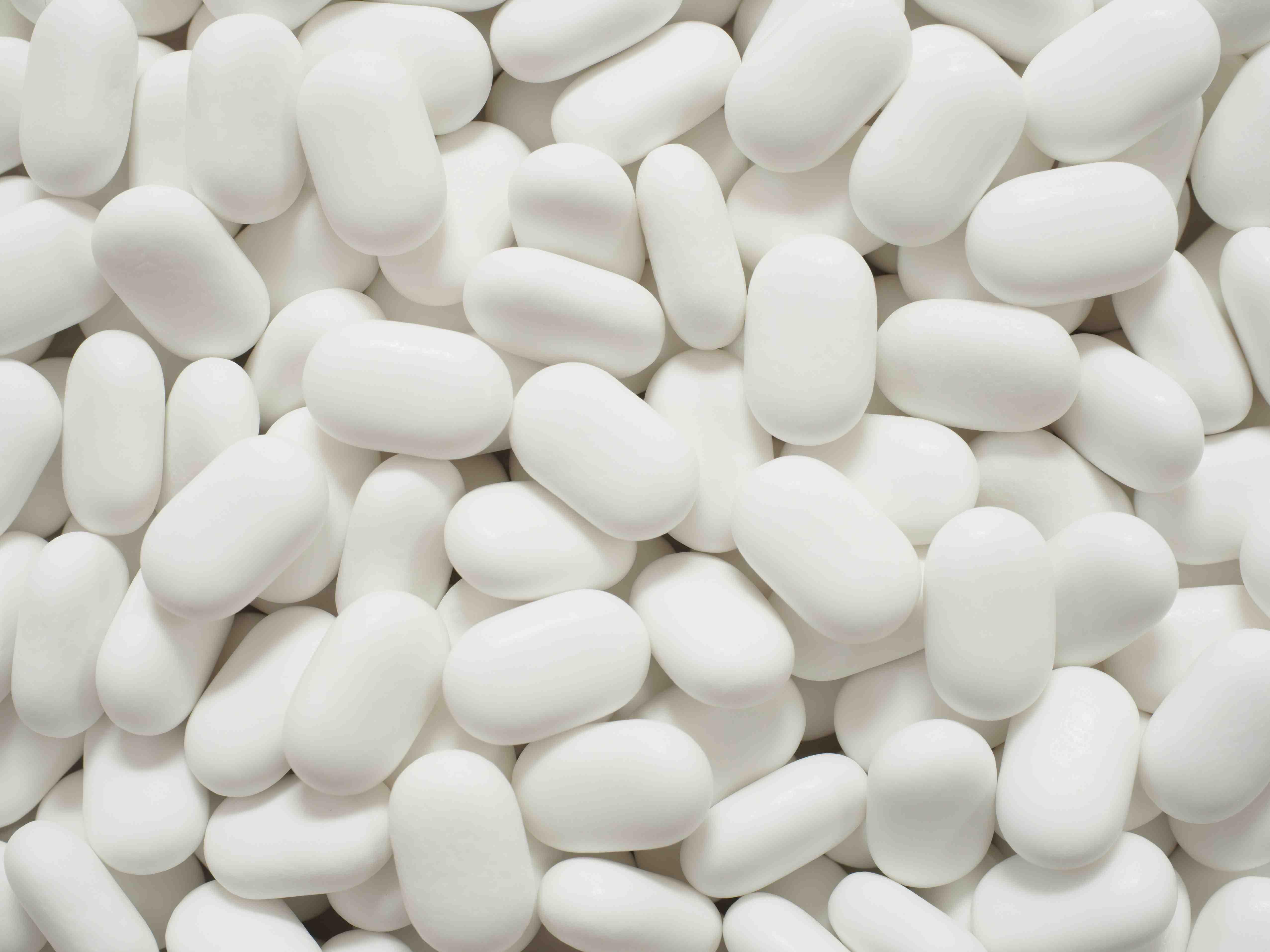 Unlabeled white pills are stacked atop one another.