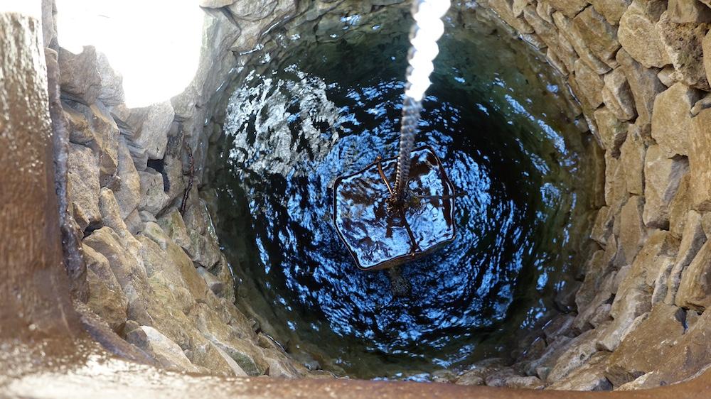 A downward shot into a well with a bucket bringing up water. 