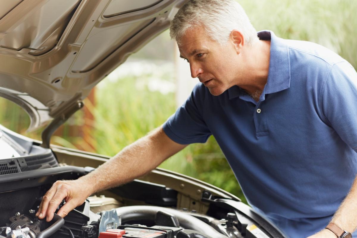 man in blue polo inspecting car engine