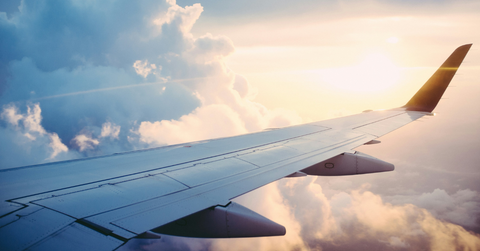 An airplane wing can be seen flying through a cloudy sky