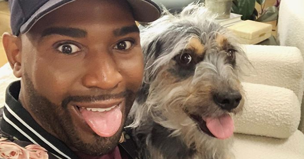 Karamo Brown and a dog stick their tongues out.