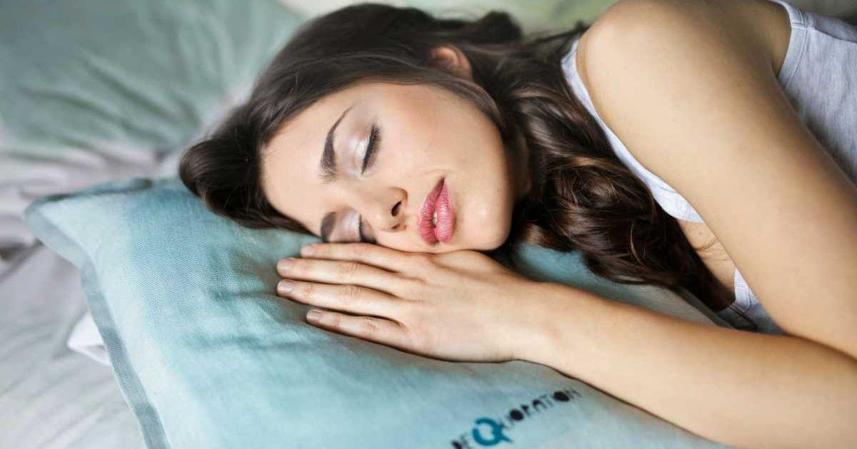 A woman sleeping calmly with her hand resting on a pastel blue pillow. (Representative Cover Image Source: Pexels | Andrea Piacquadio)