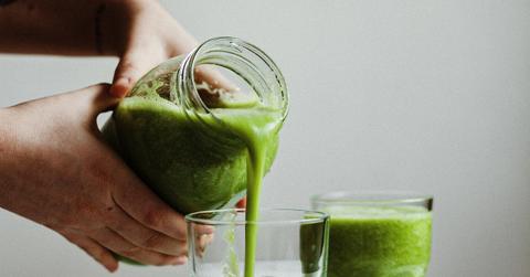 person pouring green smoothies into glasses