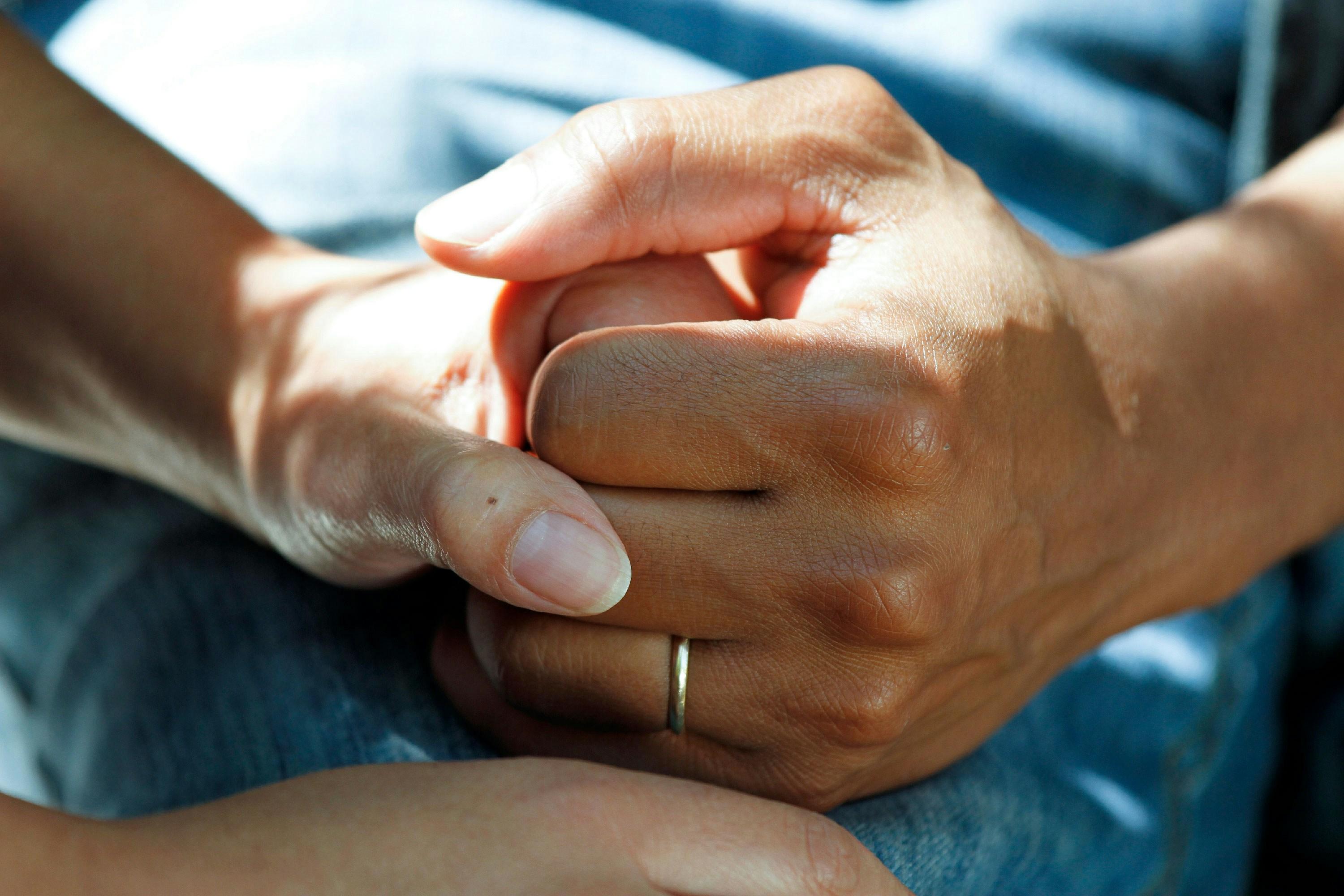 A hospital patient holds the hand of a family member.