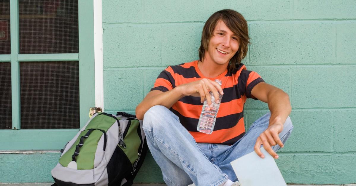 A student holds a water bottle while sitting outside of class