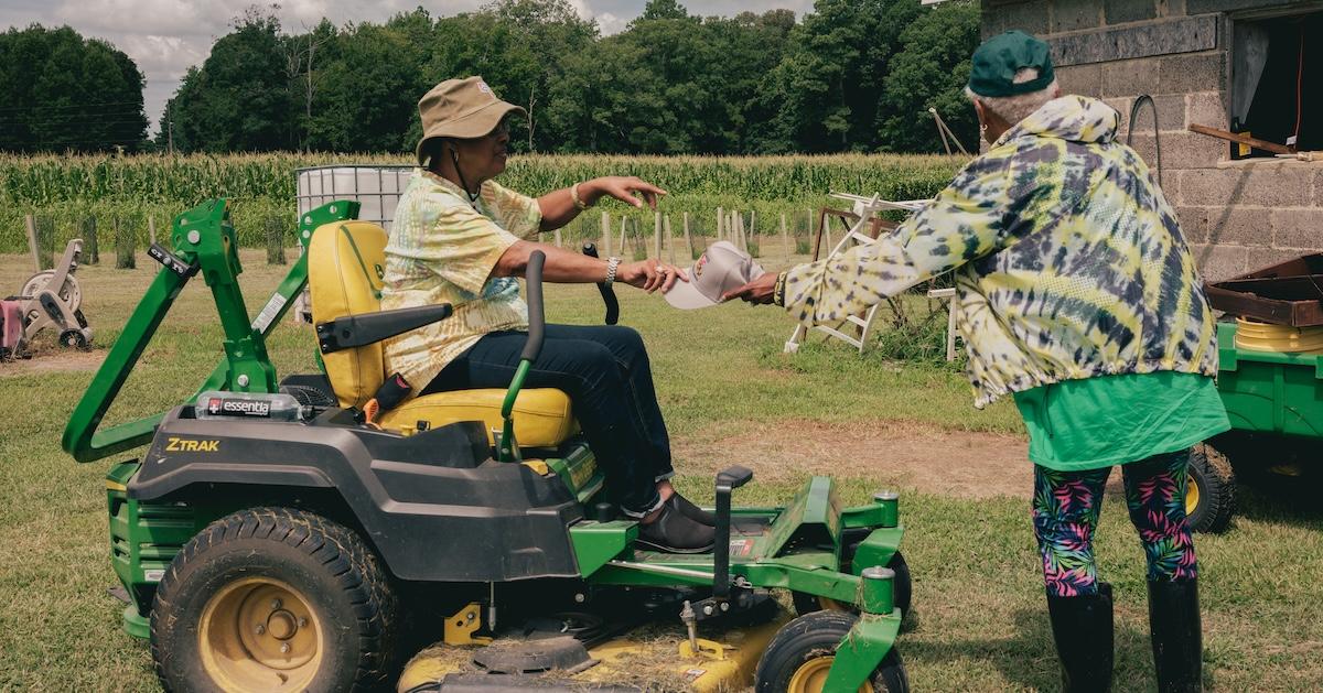  Donna Dear sits on a tractor and and Paulette Greene stands on their farm