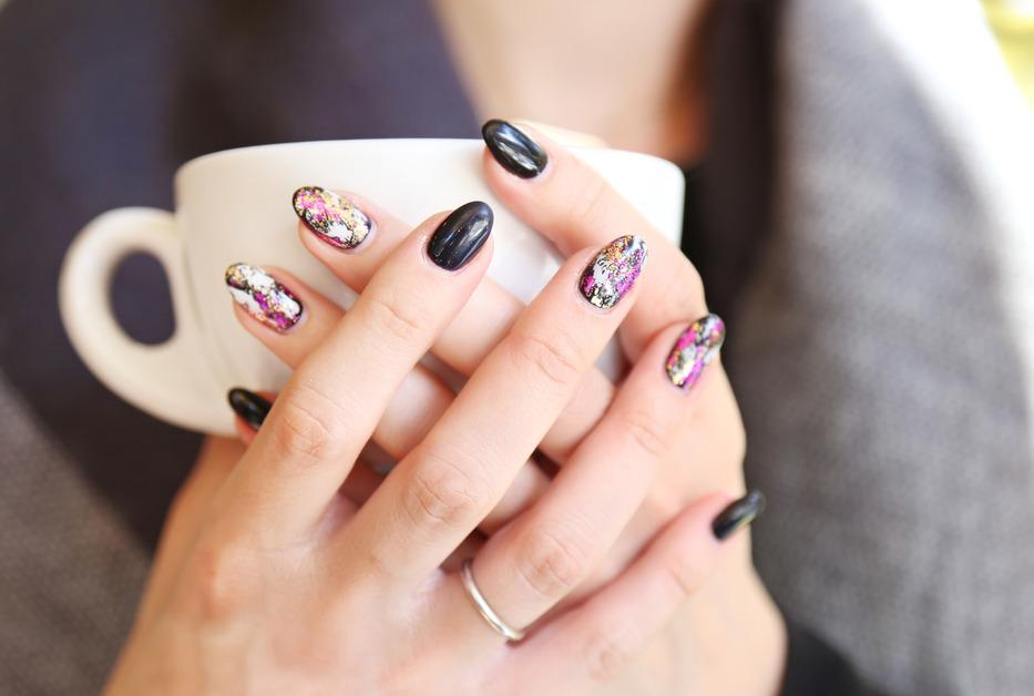 Woman holding coffee cup with black nail art. 