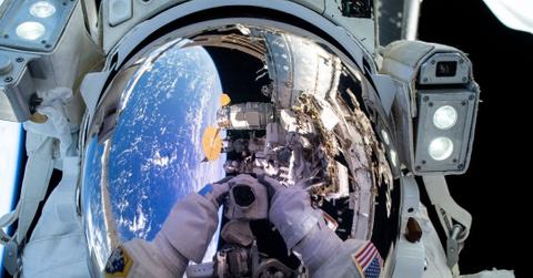 Astronaut Suni Williams takes a selfie above the Pacific Ocean with the International Space Station partially in view in the reflection of her helmet.