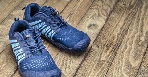 A pair of blue crossfit barefoot shoes sit on a wooden surface.