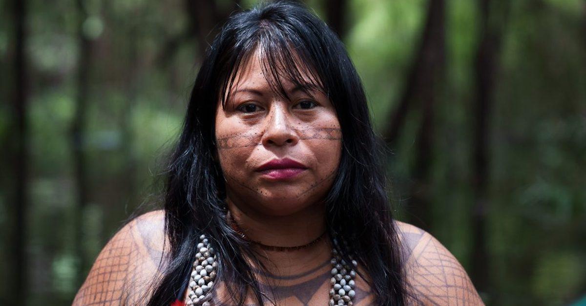 Alessandra Korap Munduruku stands in front of a forested background.