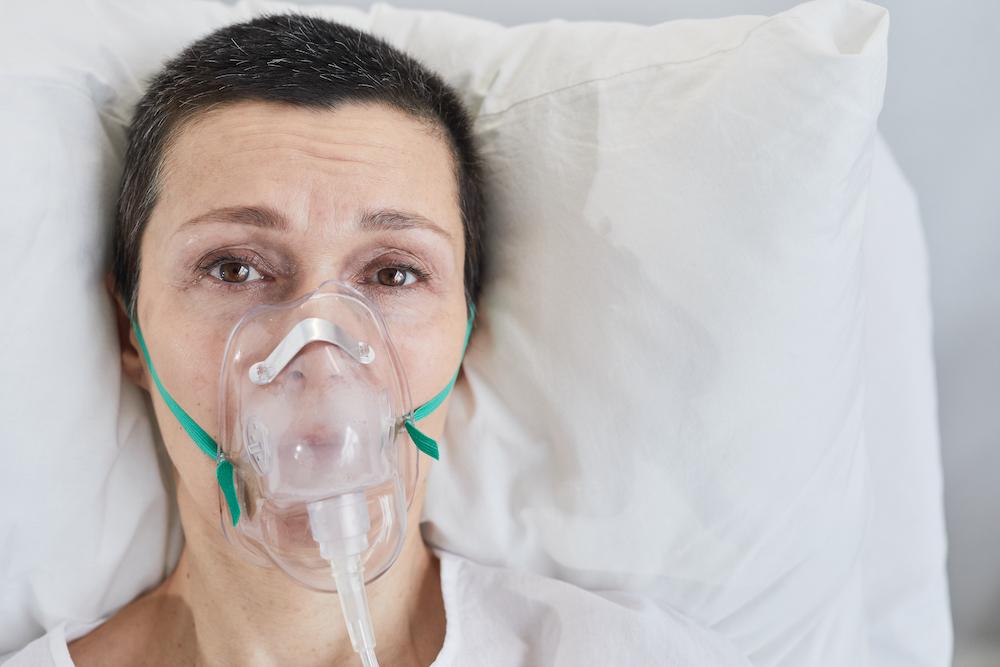 A woman in bed with an oxygen mask on.