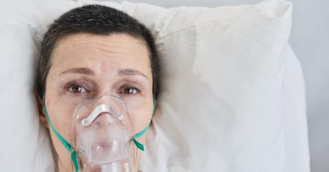 A woman in bed with an oxygen mask on.