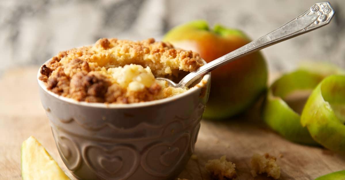 Apple crisp in a small decorative ceramic bowl with retro dessert spoon.