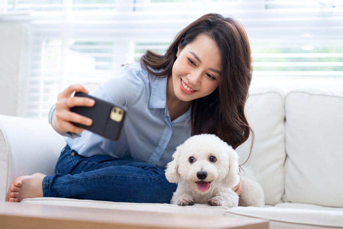 Woman taking a picture with her dog on the couch