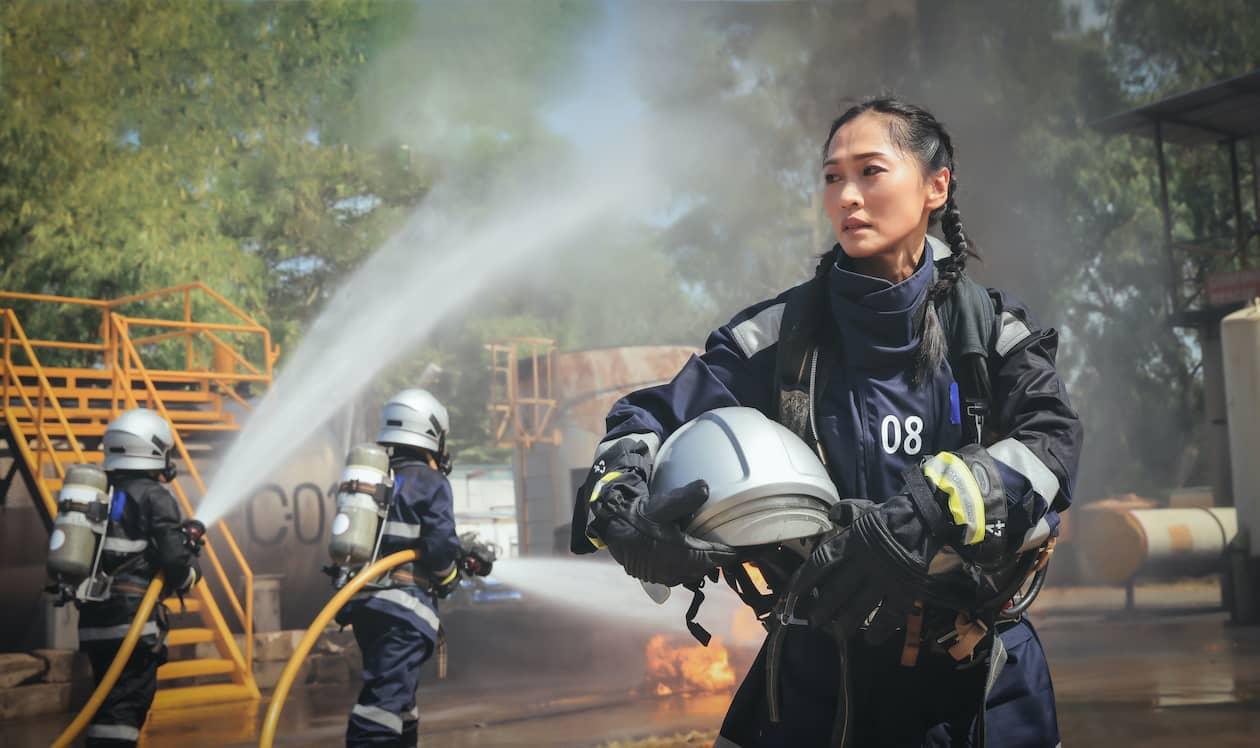 Asian woman firefighter at the scene of an accident, holding helmet