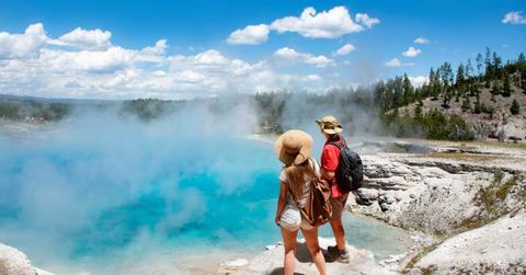 A couple enjoying the beautiful view of a geyser in Yellowstone National Park, Wyoming, USA. (Representative Cover Image Source: Getty Images | MargaretW)