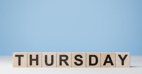 Individual letters on wooden blocks spell out the word "Thursday" against a blue and white background.