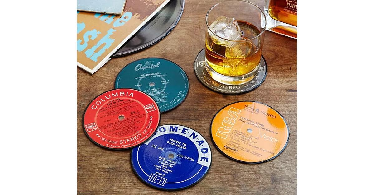 colorful coasters made of upcycled vinyl records on a wood table with an alcoholic drink on the rocks