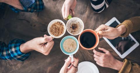 Overhead view photo of hands clinking coffee mugs