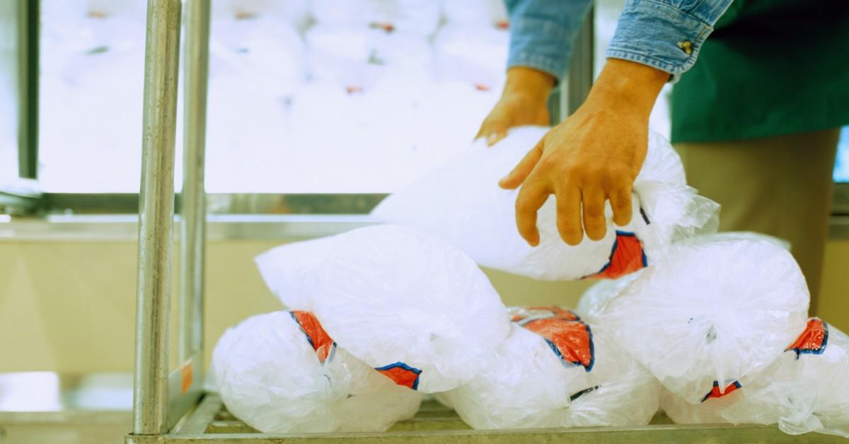 Hands placing bags of ice on a shopping cart