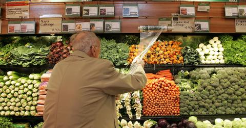 A man is getting produce at a supermarket.
