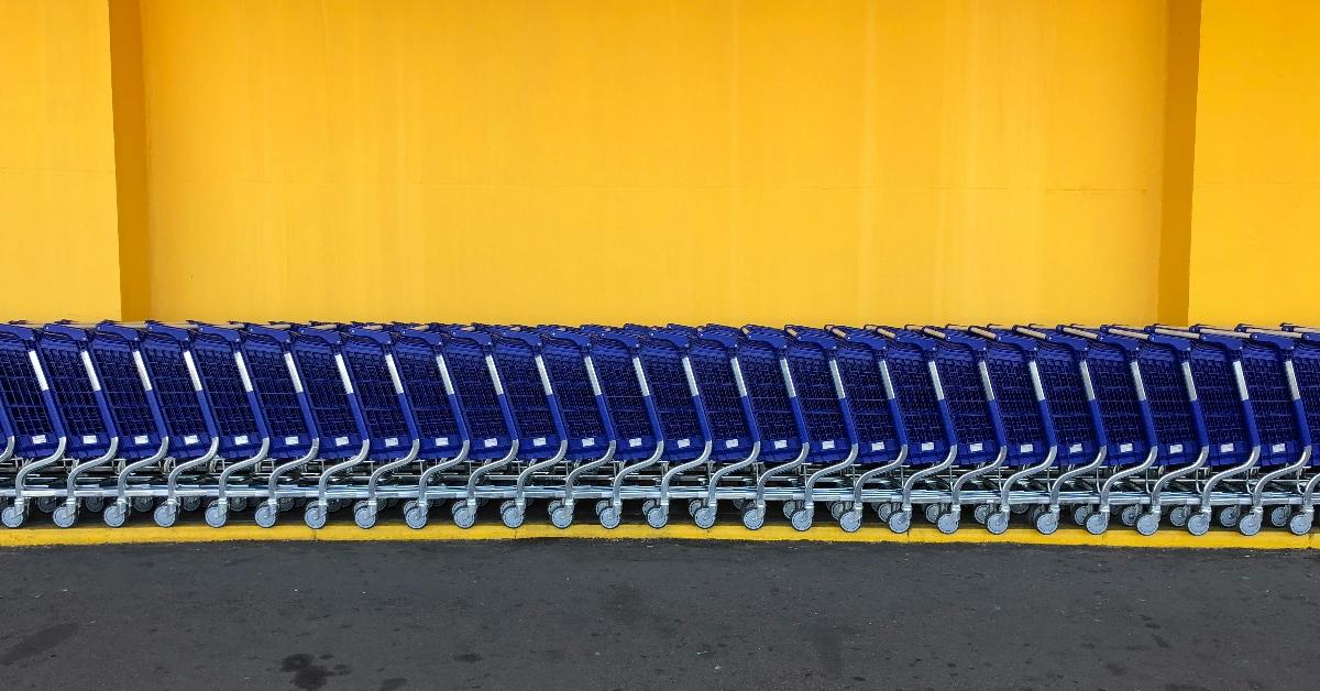 Line of blue shopping carts against a yellow back wall. 