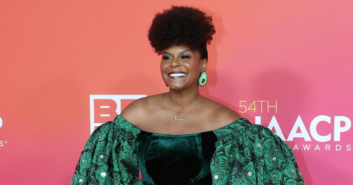 Tabitha Brown poses in a green gown in front of a pink background denoting the NAACP Image Awards.