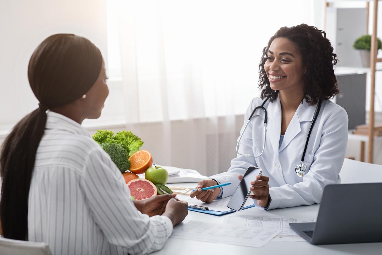 A smiling patient receives nutrition guidance from a smiling dietitian.