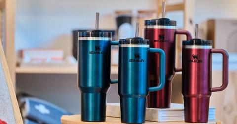 Four Stanley cups on a wooden table.