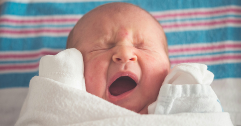 A newborn baby lays on a blanket after being born
