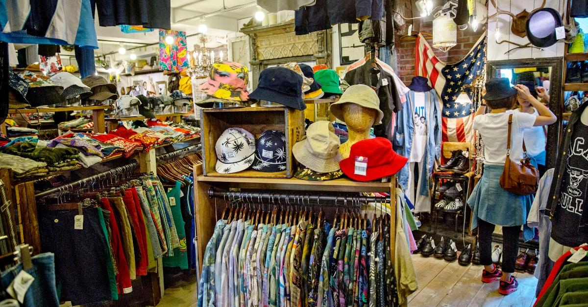 A woman trying on a hat at a thrift store. 